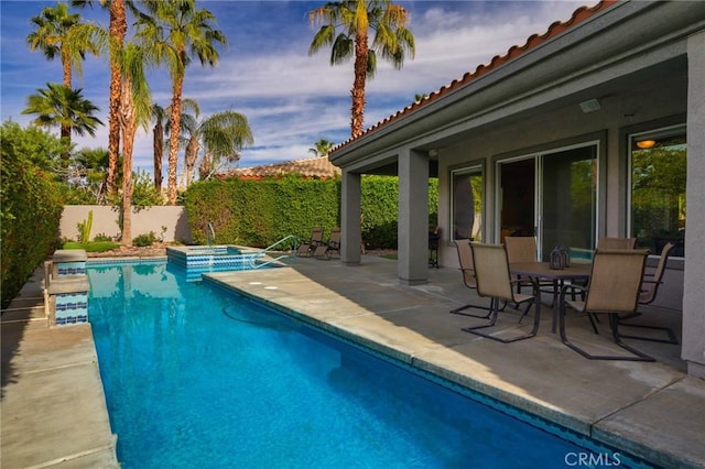 pool at dusk with a patio area and an in ground hot tub