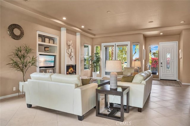 living room featuring built in shelves, a fireplace, and light tile patterned floors