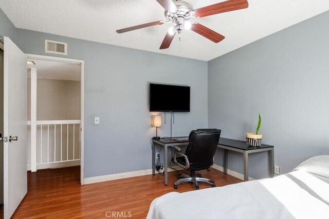 bedroom featuring hardwood / wood-style flooring, a textured ceiling, and ceiling fan