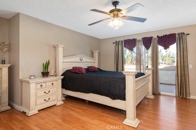 bedroom with a textured ceiling, light hardwood / wood-style flooring, decorative columns, and ceiling fan