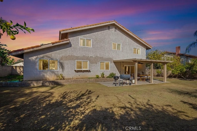 back house at dusk featuring a pergola, a yard, and a patio area