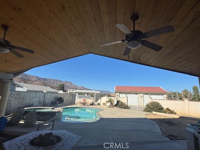 view of swimming pool featuring ceiling fan, a mountain view, and a patio area