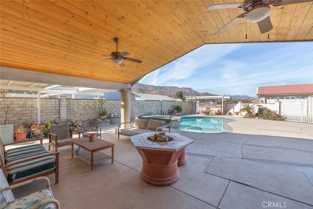 view of pool with a patio, a pool with connected hot tub, an outdoor fire pit, a mountain view, and a fenced backyard