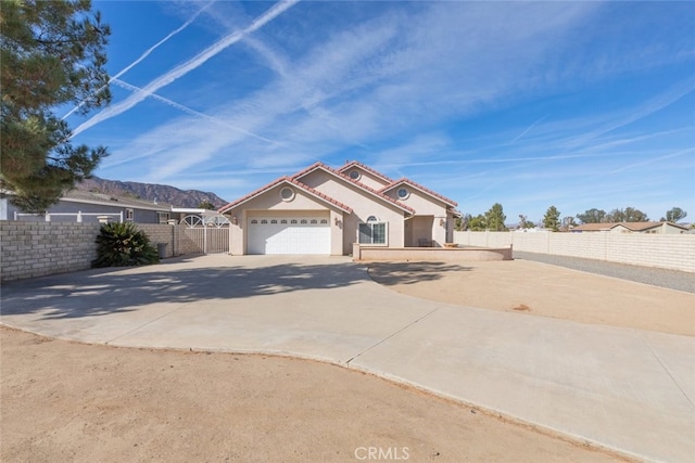 mediterranean / spanish-style house featuring a garage, concrete driveway, fence, and a tiled roof