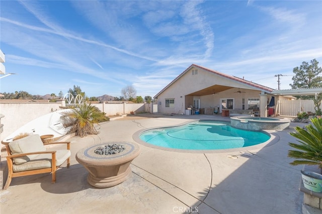 view of swimming pool with an outdoor fire pit, a pool with connected hot tub, a fenced backyard, and a patio