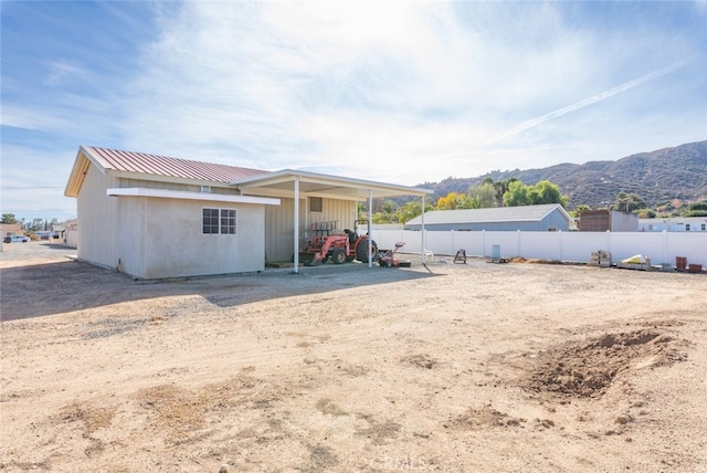 back of property with metal roof, fence, and a mountain view