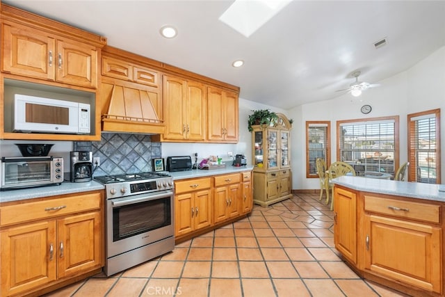 kitchen with gas range, visible vents, light countertops, and white microwave