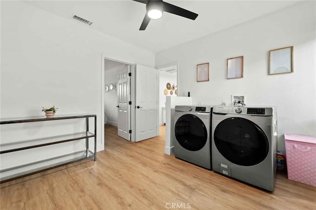 clothes washing area with ceiling fan, washing machine and dryer, and light wood-type flooring