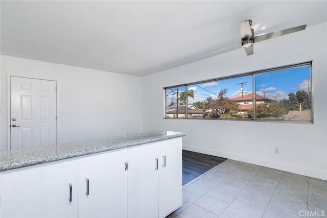 kitchen with light stone counters, white cabinets, and ceiling fan