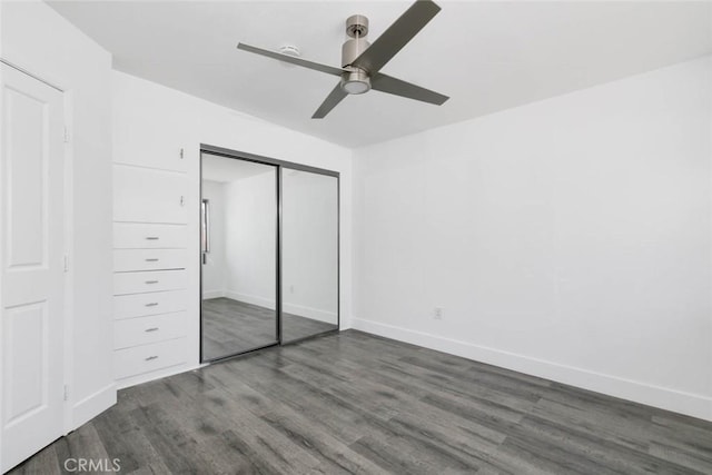 unfurnished bedroom featuring ceiling fan, a closet, and dark wood-type flooring