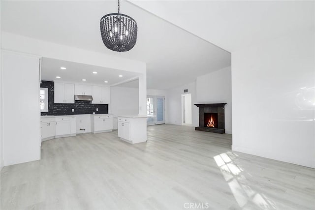 kitchen with pendant lighting, a kitchen island, white cabinetry, tasteful backsplash, and vaulted ceiling