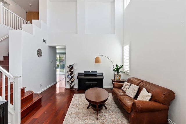 living room featuring dark hardwood / wood-style floors and a towering ceiling