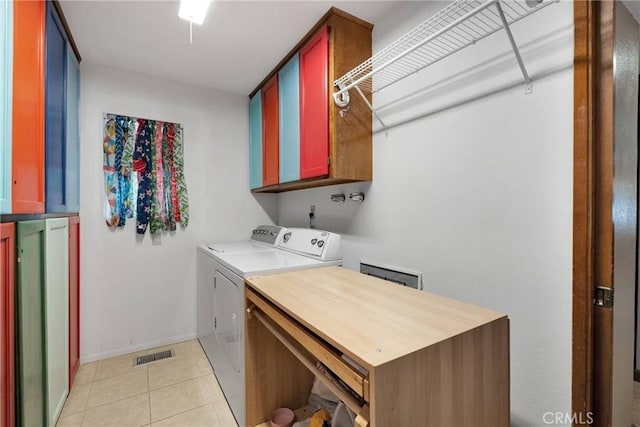 clothes washing area with cabinets, separate washer and dryer, and light tile patterned floors