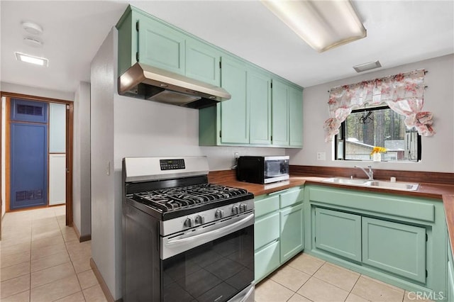 kitchen featuring sink, green cabinets, light tile patterned floors, and appliances with stainless steel finishes