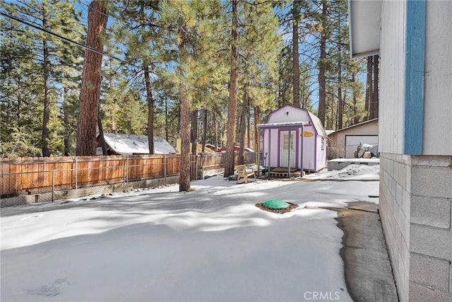 snowy yard featuring a storage shed