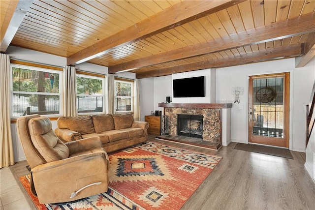 living room featuring hardwood / wood-style flooring, wood ceiling, a stone fireplace, and beam ceiling