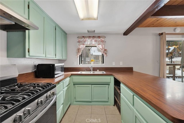 kitchen with light tile patterned flooring, butcher block countertops, sink, stainless steel gas range oven, and green cabinets