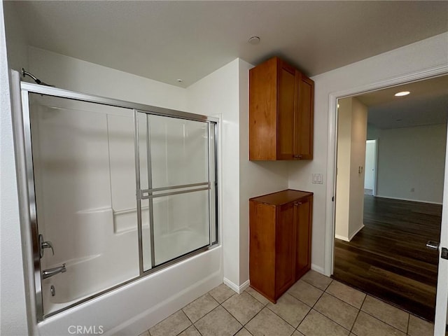 bathroom with bath / shower combo with glass door and tile patterned floors