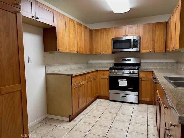 kitchen with light tile patterned flooring, stainless steel appliances, and sink