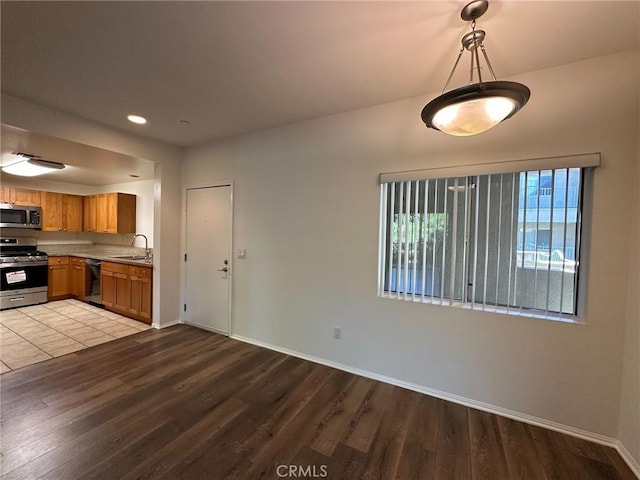 kitchen featuring light hardwood / wood-style floors, sink, hanging light fixtures, and stainless steel appliances