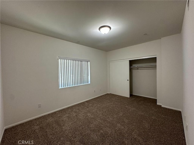 unfurnished bedroom featuring a closet and dark colored carpet