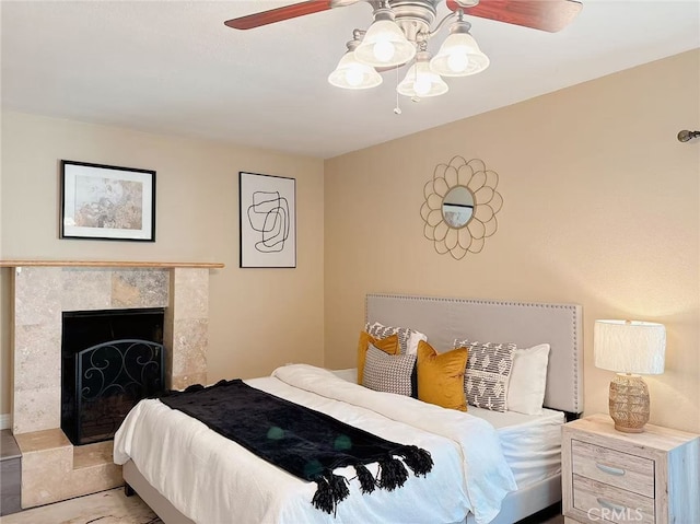 bedroom featuring a fireplace and ceiling fan