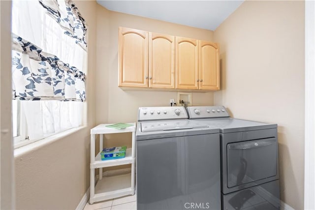 laundry room with light tile patterned floors, washer and clothes dryer, and cabinets