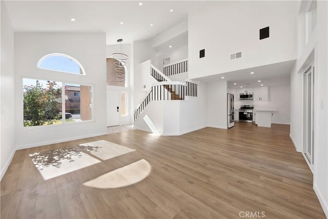 unfurnished living room featuring light hardwood / wood-style floors and a high ceiling