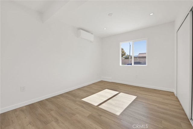 unfurnished bedroom with light hardwood / wood-style floors, a closet, and a wall mounted air conditioner