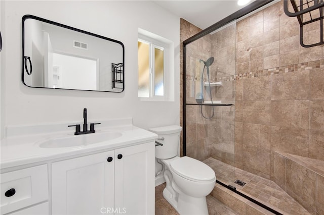 bathroom with toilet, vanity, and tiled shower