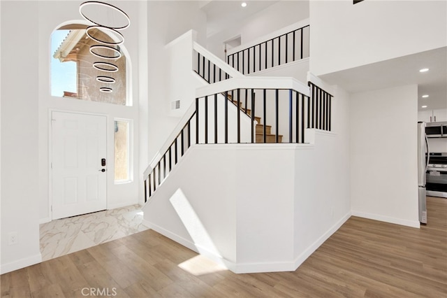 entryway featuring wood-type flooring, plenty of natural light, and a high ceiling