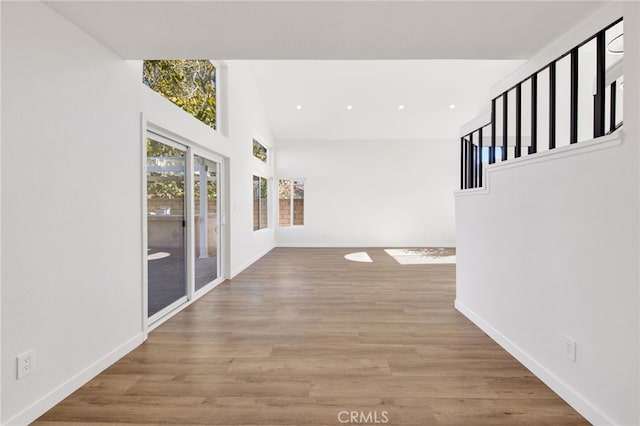 hall with light wood-type flooring and a towering ceiling