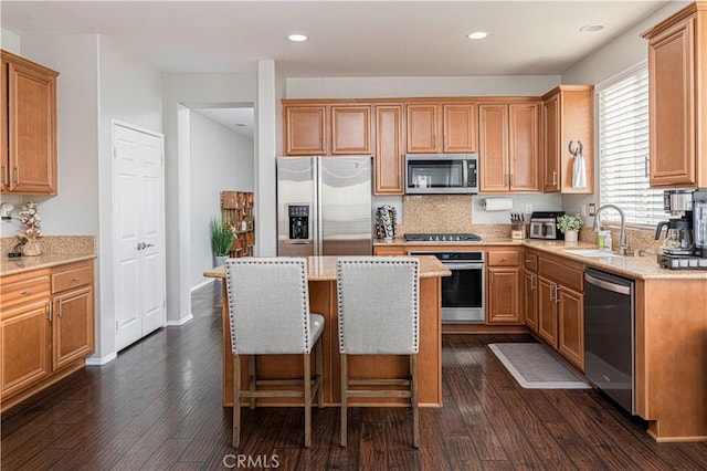 kitchen with sink, dark wood-type flooring, a kitchen island, and appliances with stainless steel finishes