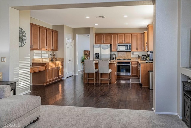 kitchen featuring tasteful backsplash, dark hardwood / wood-style floors, stainless steel appliances, and a kitchen breakfast bar