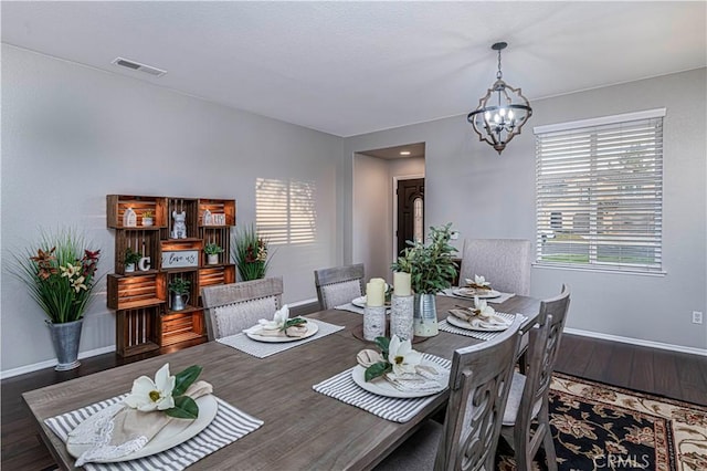 dining room featuring an inviting chandelier, plenty of natural light, and dark hardwood / wood-style flooring