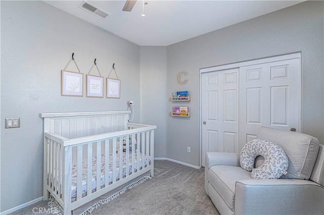 bedroom featuring a crib, a closet, ceiling fan, and carpet