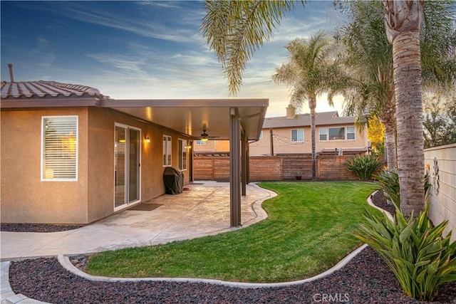 yard at dusk with a patio and ceiling fan