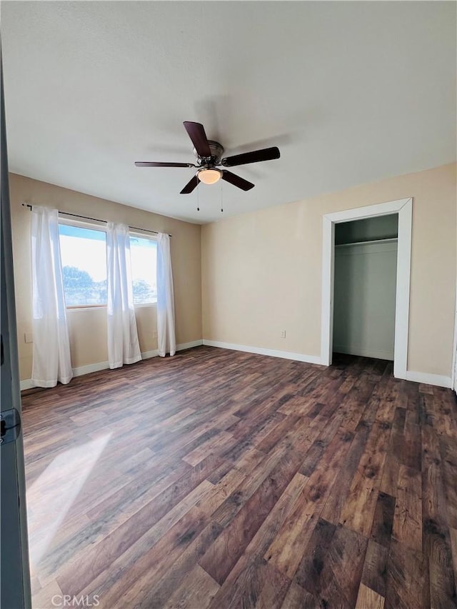 unfurnished bedroom with dark wood-type flooring, a closet, and ceiling fan