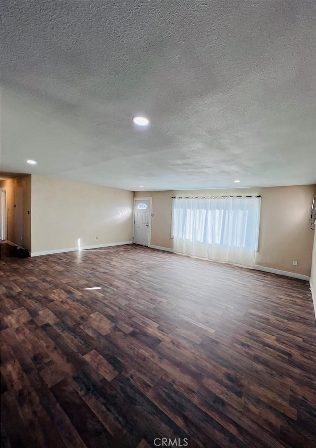 empty room with dark hardwood / wood-style floors and a textured ceiling