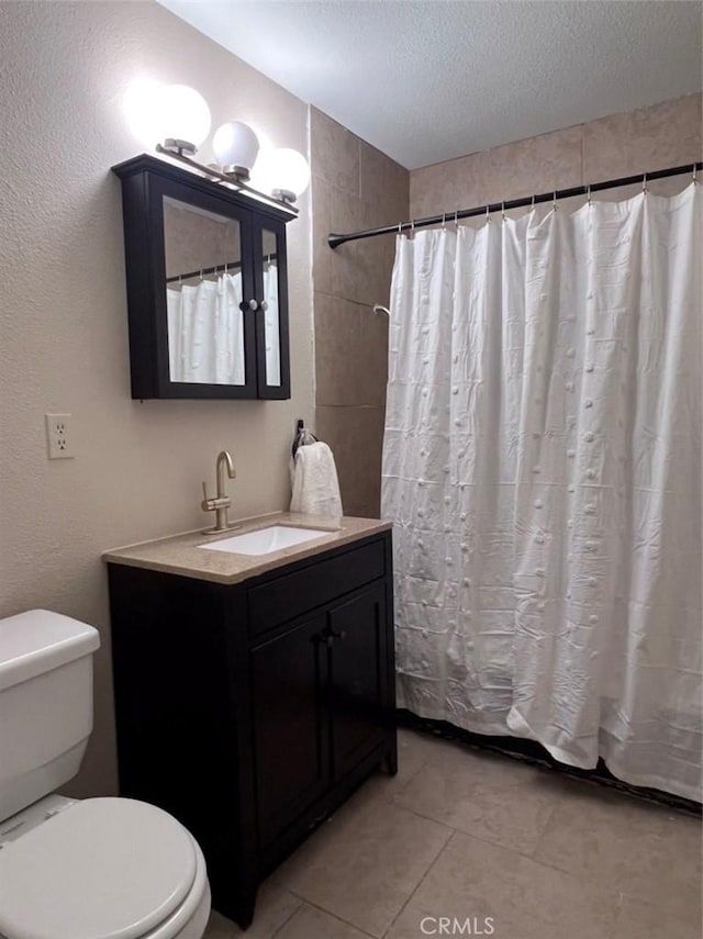 bathroom with tile patterned flooring, vanity, walk in shower, toilet, and a textured ceiling