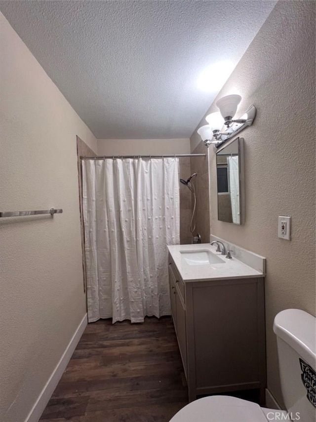 bathroom featuring curtained shower, wood-type flooring, vanity, toilet, and a textured ceiling