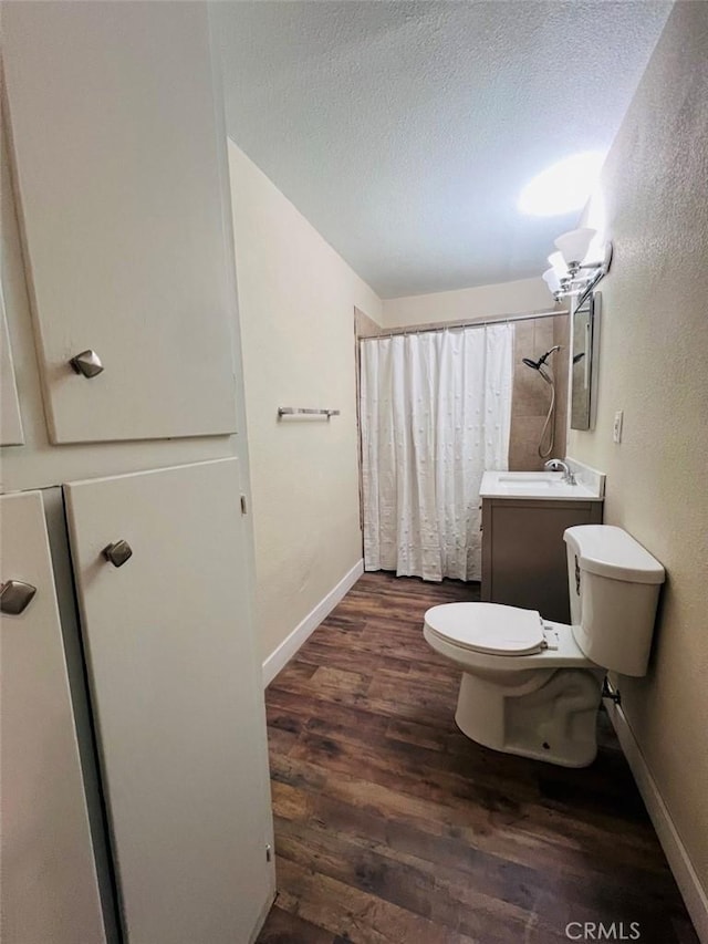 bathroom with wood-type flooring, vanity, toilet, a textured ceiling, and a shower with curtain