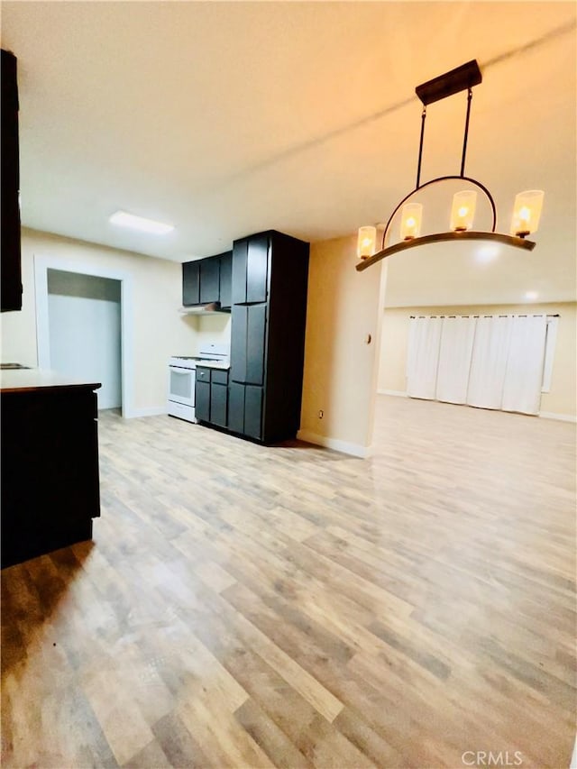 kitchen featuring black fridge, light hardwood / wood-style floors, hanging light fixtures, and white range oven