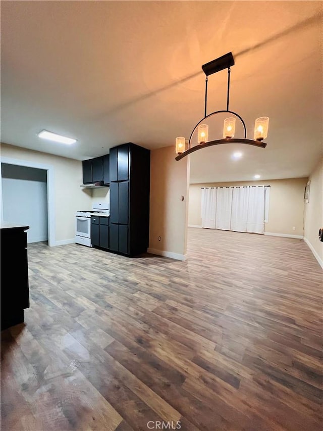 kitchen featuring black refrigerator, decorative light fixtures, dark wood-type flooring, and white gas range oven