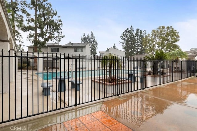 view of gate with a community pool and a patio