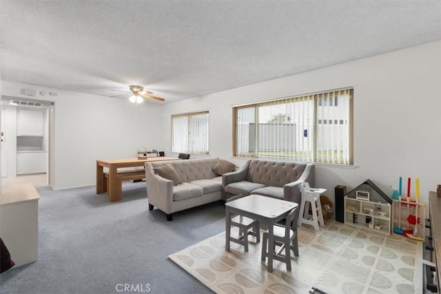 carpeted living room with ceiling fan and a textured ceiling