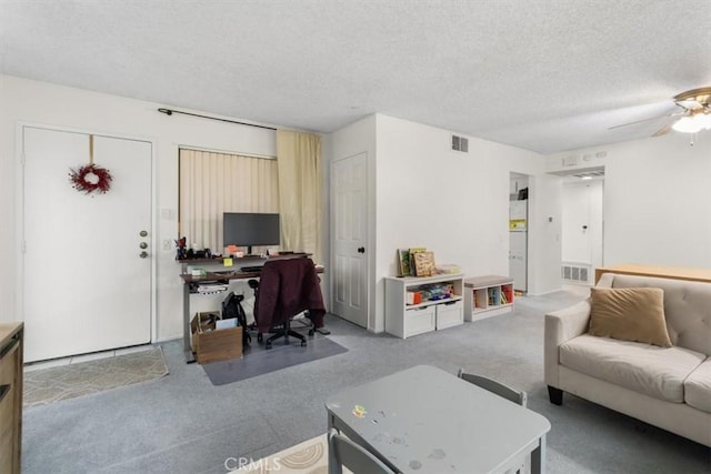 carpeted living room featuring ceiling fan and a textured ceiling