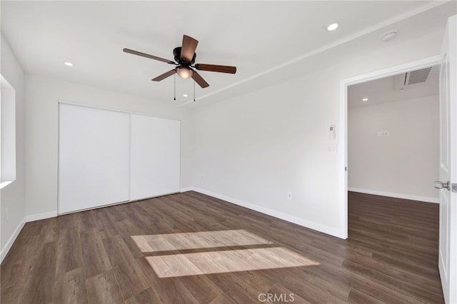 unfurnished bedroom featuring dark wood-type flooring, ceiling fan, and a closet