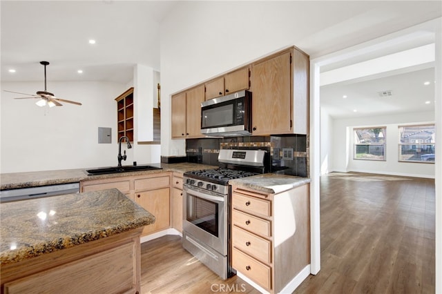 kitchen with stainless steel appliances, tasteful backsplash, stone countertops, light hardwood / wood-style flooring, and sink