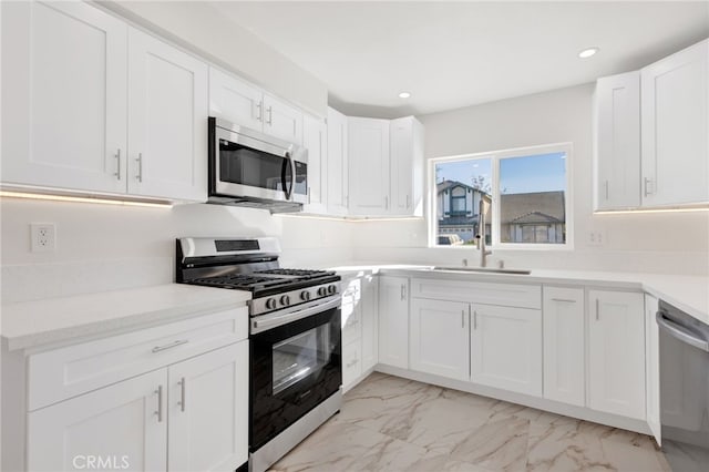 kitchen with appliances with stainless steel finishes, white cabinets, and sink